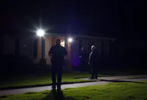 Police officers examining a crime scene outside a home at night in Indianapolis